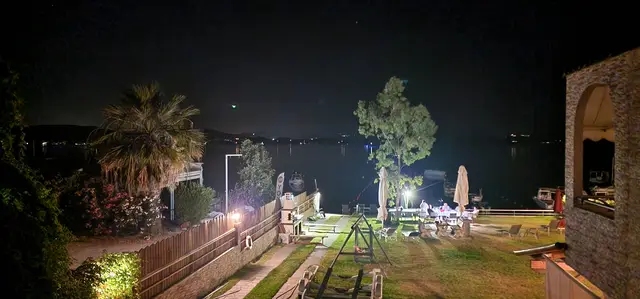 The garden and stone fireplace lit at night beside the sea