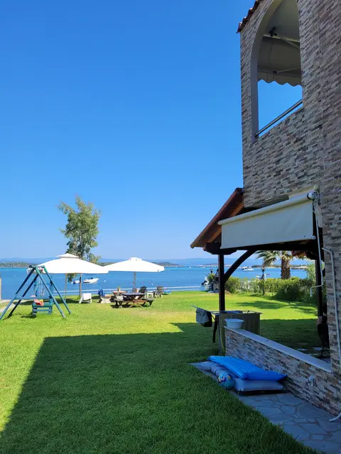 Seaside garden with swings and umbrellas on the lawn beside the house