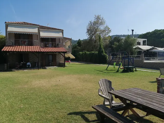 The stone house of Studios EDRA and its wide lawn with a picnic table